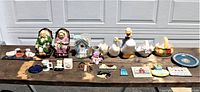Full view of all 22 assorted ceramic and novelty collectible knick knacks displayed on wooden surface with garage door backdrop
