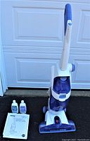 Front view of Hoover Floormate H3030 hardwood floor cleaner with bottles and manual placed beside it.
