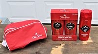 Two bottles of Old Spice Swagger body wash in a sealed red box and one single bottle next to it, plus red Old Spice travel bag with white zipper and logo.