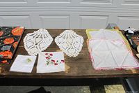 Vintage Irish linens including 2 crocheted doilies, 2 embroidered linen handkerchiefs, and 2 Halloween vinyl tablecloths visible on table.