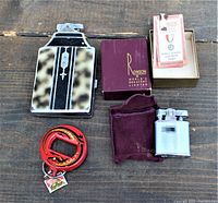 Photo shows 4 items: Ronson Princess lighter with pouch, manual, and box, Master cigarette case, Ronson De-Light lighter with pouch, and Marlboro beverage keychain.