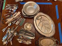 Overview of assorted flatware and several serving dishes on table