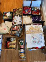 Overview of multiple boxes and baskets with assorted craft supplies including ribbons, raffia, stencils, doilies, and more.