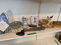 Full view of ceramic and decorative items including a blue and white vase, glass orb, bird feeder insert, carved bird figurines, bowls, and a wooden box on a white shelf.