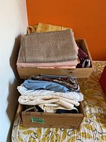 Overall view of three wooden boxes stacked with assorted folded fabric in various colors and patterns