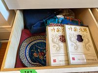 Drawer containing folded fabrics and two China Silk branded packaging envelopes showing silk fabric samples or pieces.