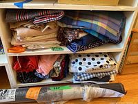 Shelf with assorted folded fabrics featuring various patterns and colors such as plaid and solids.