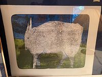 Framed artwork showing a stylized animal in pasture with blue and green colors.