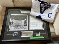 White Toronto Maple Leafs captain jersey signed by Darryl Sittler laid over framed display