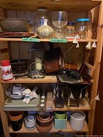 Wood shelves with assorted vases, pottery, glassware, wooden ship model and metal sailboat mobile.