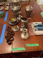 Overview: coffee pot, sugar bowl, creamer, dish, napkin rings, candlesticks, polishing cloth arranged on table