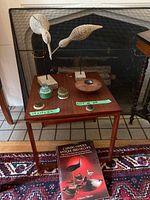 Wooden table with carved birds and flower frog holders in front of fireplace.