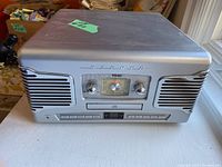 Closed view of silver TEAC stereo system showing front controls including AM/FM dial, CD slot, and speakers.