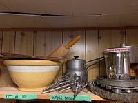 Full view of shelf displaying the ceramic mixing bowl, wooden rolling pin, wooden spoons, metal double boiler, metal baking pans including fluted tart pan, and mixer beaters grouped together.