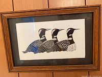 Framed loon print on wood paneling