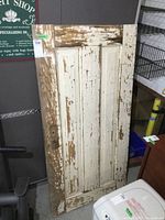 Front view of antique solid wood door, showing aged, chipped paint and four recessed panels.