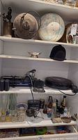 Full shelf view showing various items including the Roomba vacuum cleaner, a globe, glassware, and other miscellaneous items.