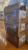 Three boxed Untrammelite LED pendant lights stacked, boxes labeled with product info and dimensions