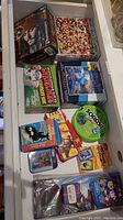 Top-down view of various puzzle and board game boxes, including Pirates of the Caribbean Photomosaics, Christmas Scavenger Hunt, Sorry, and several smaller game sets.