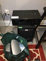 Sony AV receiver shown on top with Polk Audio subwoofer below and surround speakers in green bag in front.