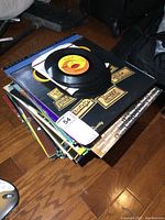 Top view of stack of LP vinyl records with several 7-inch 45 RPM records on top, showing some wear on sleeves and labels