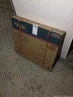 Sealed box containing the Style Selections black umbrella stand. Box shows brand and product name.