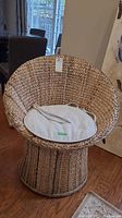 Front view of vintage wicker basket chair showing round edges and seat cushion.