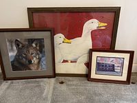 Three framed art pieces including a wolf photograph and goose quilt art.