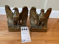 Pair of brass American Eagle bookends side by side on wood floor.