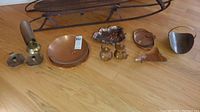 Full view of all copper household items including candle holders, round platter, ashtray shaped like a leaf, basket and sugar and creamer pots.