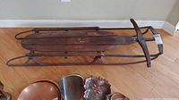 Side view of the vintage Airline Junior sled showing the wooden slats and steel runners with signs of rust and wear.