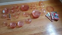 Overall view of pink Depression glass pieces and four books on hardwood floor.