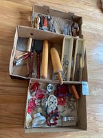 Assortment of kitchen utensils in boxes, including rolling pins, whisks, spatulas, and nutcracker