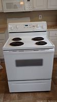 Front view of white Whirlpool electric stove with coil burners and oven door with window.
