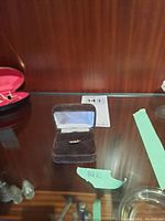 14K gold thin band ring displayed in a dark brown velvet ring box with satin interior lining, placed inside a glass case.