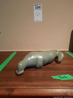 Side profile of green jade animal carving showing smooth polished surface and general shape.