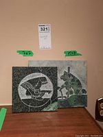 Two stone carvings side by side showing carved Indigenous figures in green and gray stones. Artist David Bernett's signature visible.