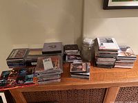 Wide view of multiple stacks of CDs on wooden cabinet with various jazz and classical albums visible