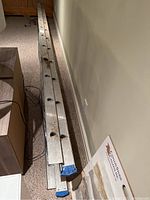Long aluminum extension ladder laid out horizontally along a carpeted floor, showing length and overall condition.