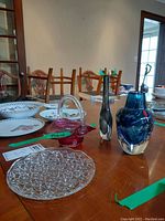 Photo shows three colored art glass vases and clear glass candy dish with intricate starburst pattern on a wooden table