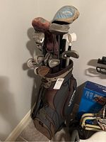 Full Callaway golf bag with clubs and covers in corner