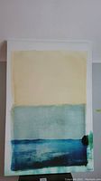 Photo showing entire abstract painting with muted yellow, greenish-blue, blue, and black sections.