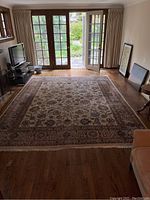 Full room view showing entire rectangular rug on hardwood floor beneath windows and doors.