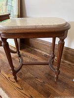 Side table showing wooden base with four carved legs and oval marble top