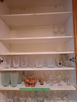 Shelves showing multiple types of glassware including crystal cut glass tumblers, frosted tumblers, wooden egg cups, and clear stemware glasses.