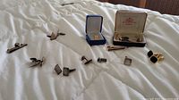 Multiple cufflinks and tie accessories arranged on quilt