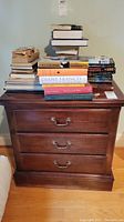 Nightstand with stack of books on top, showing overall front view.