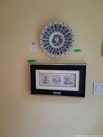Photo showing the framed three Portuguese art tiles and the large decorative wall plate hung above on a wall.