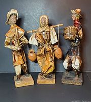Front view of three Mexican paper mache figurines showing detailed clothing and features
