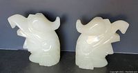 Pair of carved alabaster/onyx bookends showing Native American warriors with eagle headdresses side-by-side on a black surface.